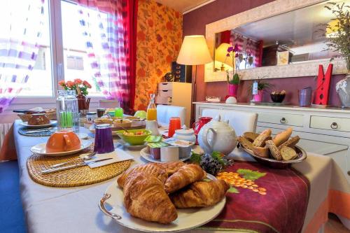 a table with bread and croissants on it in a kitchen at Chambres & Table d'hôtes La Bordelaise in Cenon