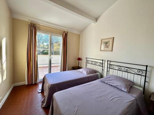 deux lits dans une chambre avec une fenêtre dans l'établissement Les Restanques 21 pins 7pers, à Grimaud