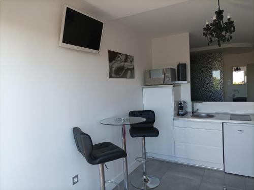 een keuken met 2 krukken en een tafel in een kamer bij Village Naturiste Studio Luxe in Cap d'Agde