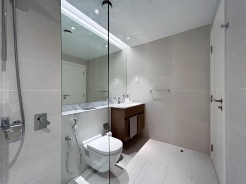 een badkamer met een toilet en een glazen douche bij Trophy - Mykonos-Inspired La Mer Suite in Dubai