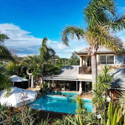 an exterior view of a house with a swimming pool and palm trees at Aloe Village Aparthotel & Spa in La Paloma