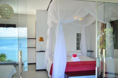 a bedroom with a bed with a white canopy at Pousada Ponta Das Pedras in Morro de São Paulo