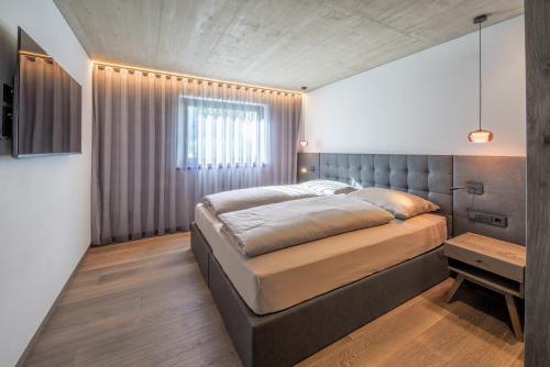 a bedroom with a large bed and a window at Köfele Lodge Rosa in Parcines