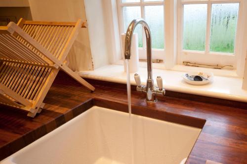 a kitchen sink with a faucet next to a window at Old Coastguards - Stunning Historic Cottage in Totland