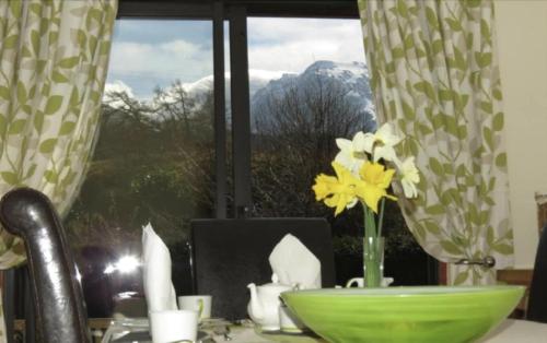 a table with a vase of flowers and a window at Mayfield B&B in Fort William