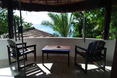 a table and chairs in a room with a view of the ocean at Pousada Ponta Das Pedras in Morro de São Paulo