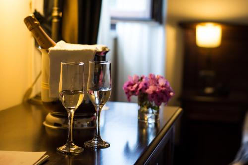 two glasses of wine and a vase of flowers on a counter at Antica Stazione in Chiaramonte Gulfi