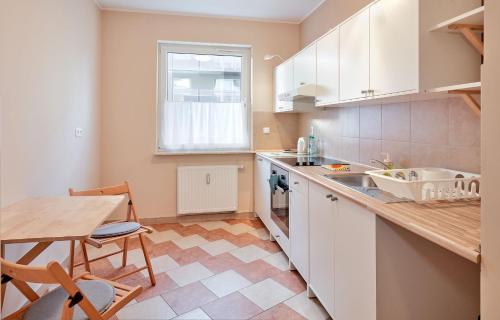 une cuisine avec des placards blancs, une table et une salle à manger dans l'établissement Osiedle Zwycięstwa Standard Apartment, à Poznań