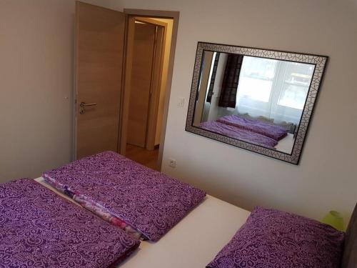 Schlafzimmer mit lila Bettwäsche auf einem Bett und einem Spiegel in der Unterkunft Zagreb apartment in Zagreb