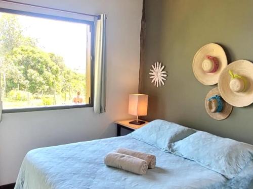 a bedroom with a bed and a window with hats at Pousada da Lua in Delfinópolis