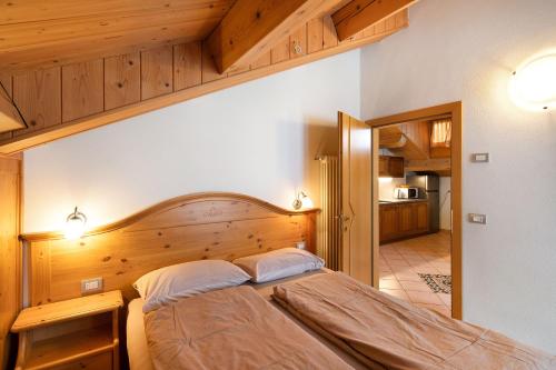 een slaapkamer met een groot bed met een houten hoofdeinde bij Appartamento Piz Saliente in Livigno