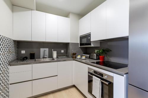 une cuisine avec des armoires blanches et des comptoirs noirs dans l'établissement La Roseraie Bidart, Piscine, Golf d Ilbaritz, à Bidart