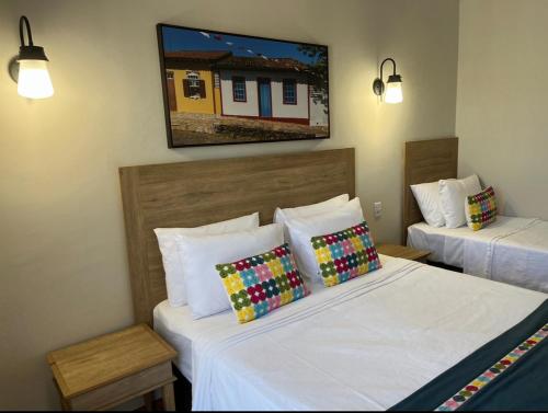 a hotel room with two beds and a tv on the wall at Quinta Santa Bárbara in Pirenópolis