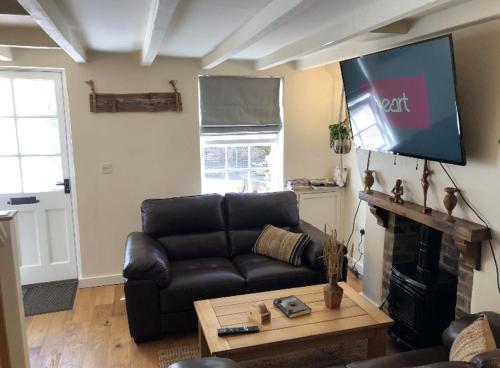 a living room with a black leather couch and a flat screen tv at 2 Bed Cottage - Sleeps 4 - Parking - Wifi in Bridgnorth