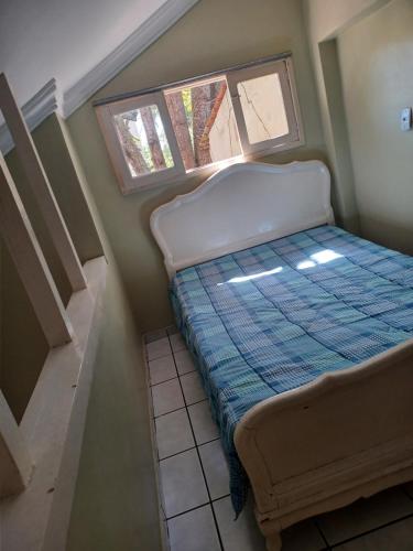 ein kleines Schlafzimmer mit einem Bett und zwei Fenstern in der Unterkunft Kitnet Praia Jacaraipe in Serra