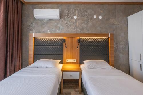 a room with two beds and a clock on the wall at Sunday Beach Hotel in Kusadası