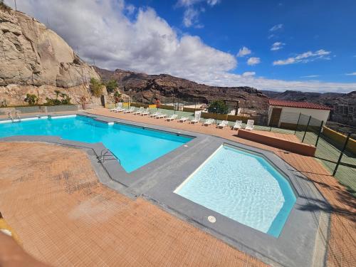 una piscina con una montaña al fondo en CASA TONINO, en Mogán