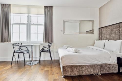 - une chambre avec un lit, une table et des chaises dans l'établissement Golden Square, à Londres