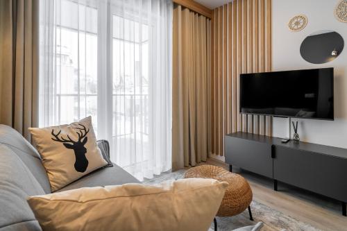 a living room with a couch and a flat screen tv at RentPlanet - Apartamenty Zakopiańskie in Zakopane