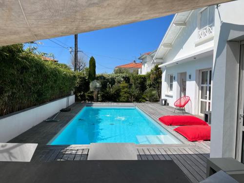 a swimming pool with red pillows next to a house at Biarritz, Castellamare, Magnifique maison avec piscine in Biarritz