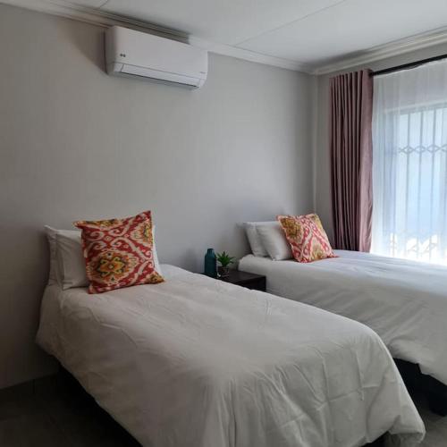 ein Schlafzimmer mit zwei Betten und einem Fenster in der Unterkunft Bloom cottage, Specious with solar back up! in Kempton Park