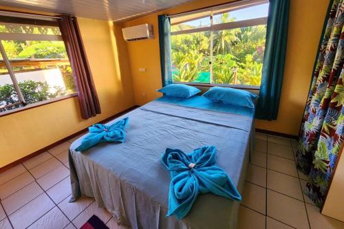 a bedroom with a bed with blue bows on it at FARE Miti en bord de mer Fare Tepua Lodge in Uturoa