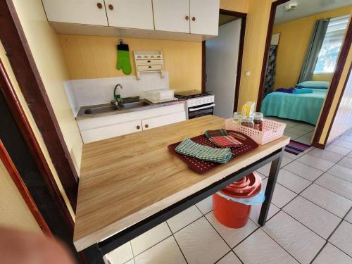 een keuken met een tafel en een wastafel in een kamer bij FARE Miti en bord de mer Fare Tepua Lodge in Uturoa