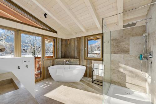 a bathroom with a tub and a glass shower at Chalet Alpspitze - Riverside in Garmisch-Partenkirchen
