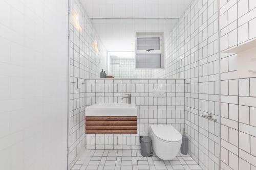Baño de azulejos blancos con aseo y lavamanos en Seaside 8, en Ciudad del Cabo
