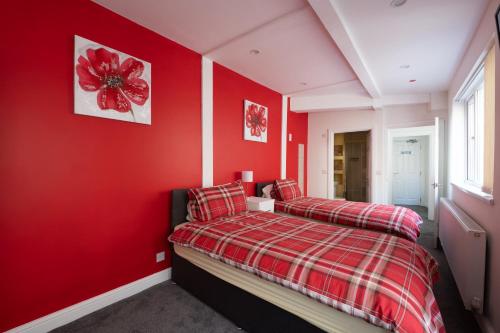 a red bedroom with two beds and a red wall at Central Tenby North Beach Apartment with Parking in Pembrokeshire
