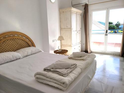 Un dormitorio blanco con una cama con toallas. en NPG429 - Holiday Beach House on the Golf Course, en Huelva