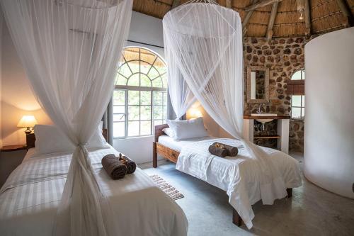 Mobola Lodge في Mamono: غرفة نوم بسريرين ذات ستائر بيضاء