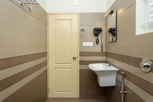 a bathroom with a sink and a phone on the wall at ESAA Airport Hotel in Cochin