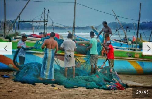 a group of men working on a boat on the beach at Raymond Place -REDSTAR in Weligama