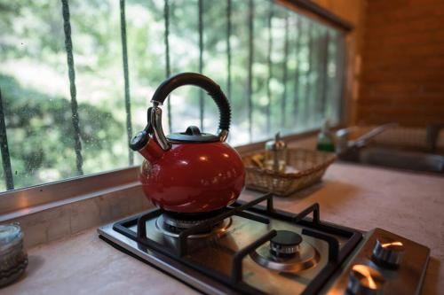a red tea kettle on a stove in a kitchen at The Red Cabin at the bottom of Tepoztlán's Forest in Tepoztlán