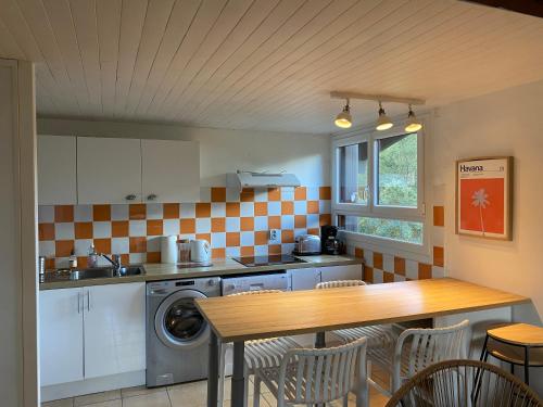 - une cuisine avec une table, un évier et un lave-linge dans l'établissement Résidence MARENSIN. Appartement duplex, proche de la plage des Bourdaines, à Seignosse