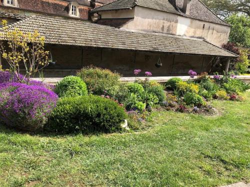 Ein altes Gebäude mit Büschen und Blumen in der Unterkunft Le Clos des Eaux in Tailly