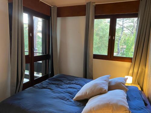 - un lit avec deux oreillers dans une chambre dotée d'une fenêtre dans l'établissement Résidence MARENSIN. Appartement duplex, proche de la plage des Bourdaines, à Seignosse