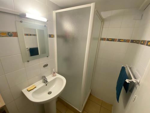 une salle de bain blanche avec un lavabo et une douche dans l'établissement Résidence MARENSIN. Appartement duplex, proche de la plage des Bourdaines, à Seignosse
