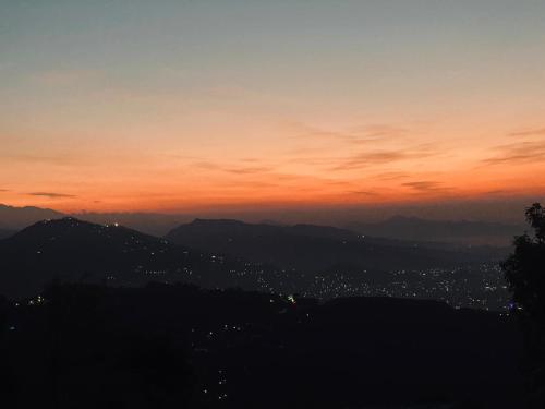 a view of a city at sunset at Hom's Homestay Retreat Sarangkot Pokhara in Pokhara