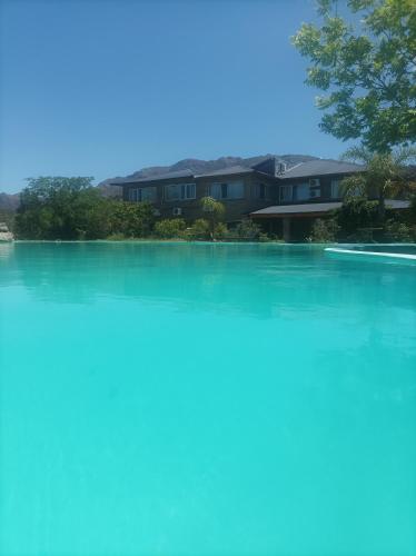 uma grande piscina de água com casas ao fundo em Posada el antiguo refugio em Potrero de los Funes