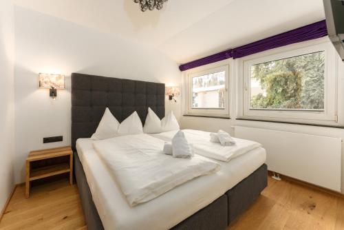 a bedroom with a large bed with white sheets and a window at Villa Waluliso by Schladming-Appartements in Schladming