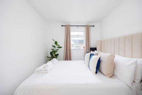 una camera da letto con un grande letto bianco con cuscini di Stylish 2-Bed East London Home Contractors Parking Sleeps 5 Near ExCeL London a Londra