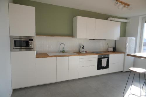 une cuisine avec des armoires blanches et un évier dans l'établissement Grand appartement 80m² - Suite parentale, à Villeurbanne