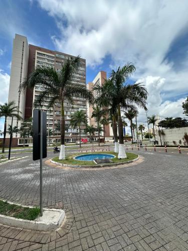 a courtyard with palm trees in front of a building at Comfortable & Economic Acqua Village in Brasilia