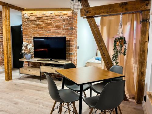 comedor con mesa, sillas y TV en Brick and Wood Apartment en Bydgoszcz