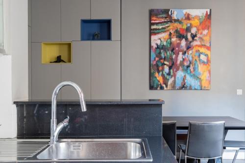 une cuisine avec un évier et un tableau mural. dans l'établissement Veeve - The Artist's Residence, à Paris