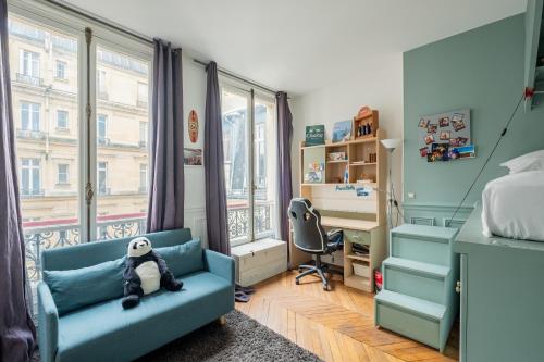 - une chambre avec un canapé bleu, un bureau et une fenêtre dans l'établissement Veeve - The Artist's Residence, à Paris