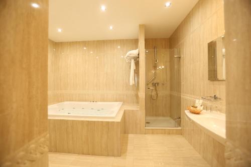 a bathroom with a tub and a sink and a shower at Navaria Nova in Lviv