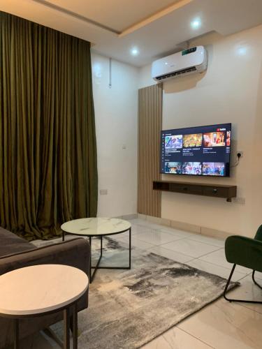 uma sala de estar com duas mesas e uma televisão de ecrã plano em Luxury apartments em Ibadan